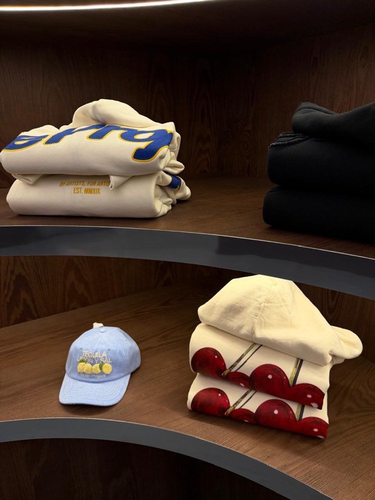 Estantes con buzos y gorras en el local de Nude Project