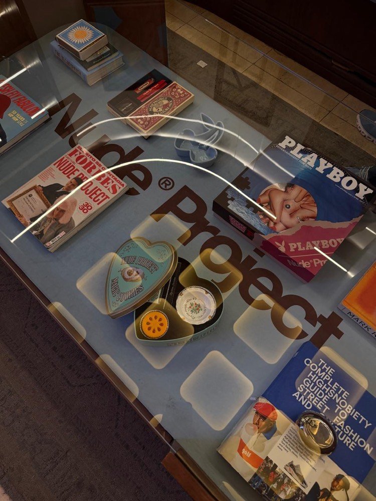 Mesa de exhibición con revistas y objetos en Nude Project